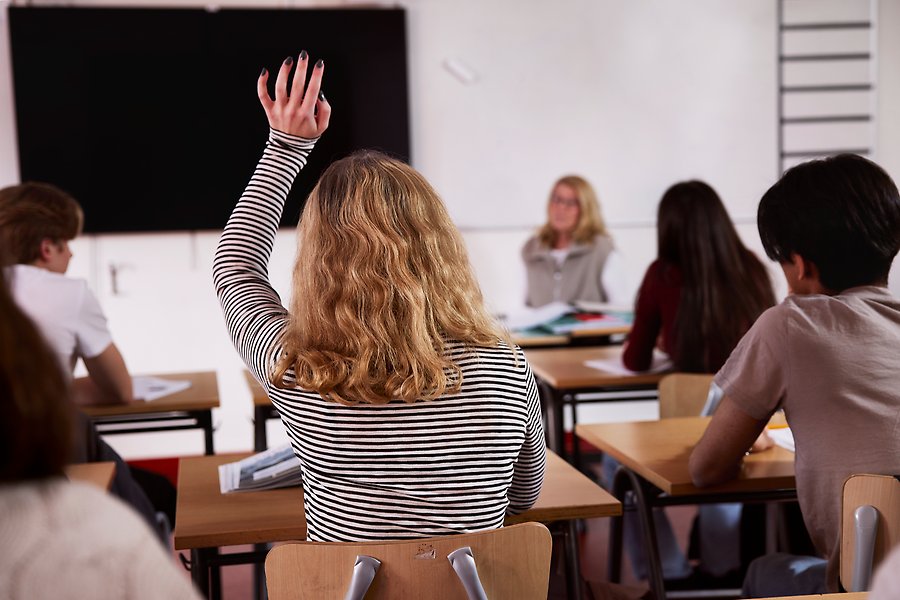 Elev räcker upp handen i klassrum.