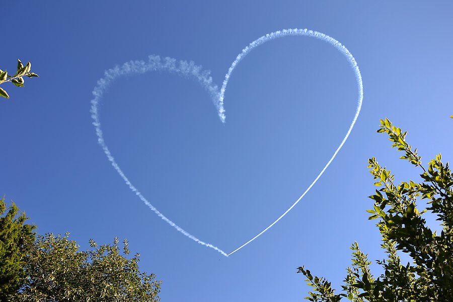 Flygplansrök som formar ett hjärta på himlen.