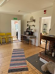 Ett rum i torpet. På golvet finns en matta och till höger en öppen spis.