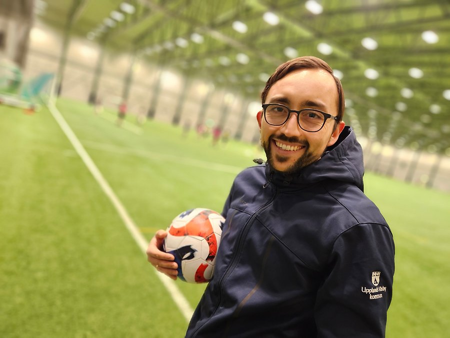 Felipe Illezca Barria står med en fotboll i famnen vid fotbollsplanen i Fotbollshallen.